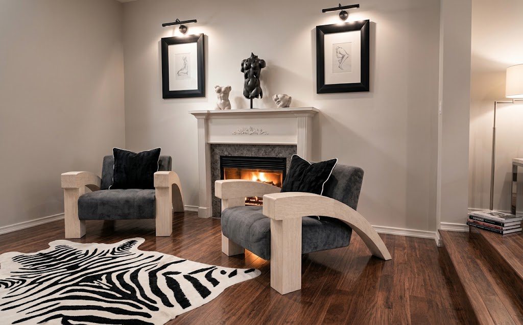Sitting room in The White Veld Regency style: sculptural armchairs, zebra-print rug, classical busts, and black-framed line drawings by the fireplace
